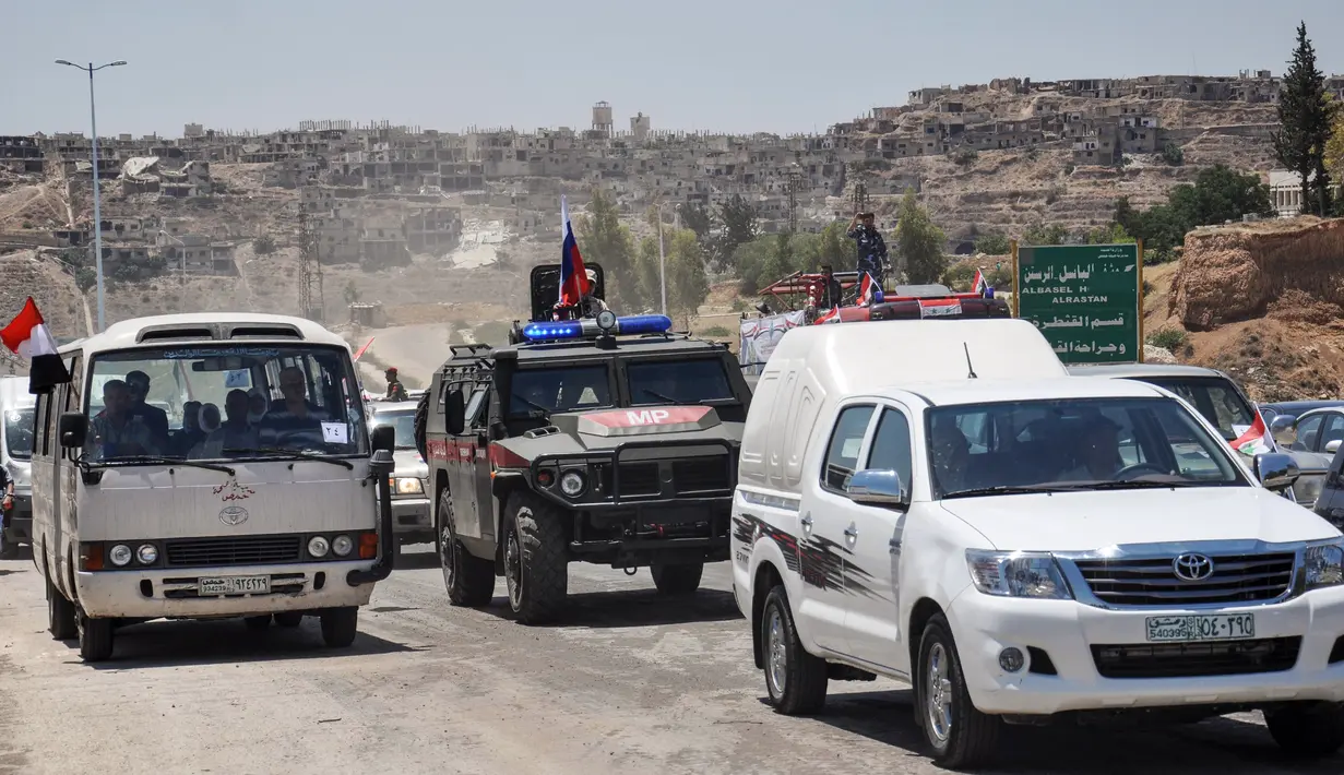 Mobil-mobil pemerintah dan kendaraan militer Rusia melintasi jalan raya utama antara Homs dan Hama di Suriah, Rabu (6/6). Pembukaan jalan itu dilakukan sebulan setelah pasukan Suriah merebut kembali wilayah kantong yang dikuasai militan itu (AFP/STRINGER)