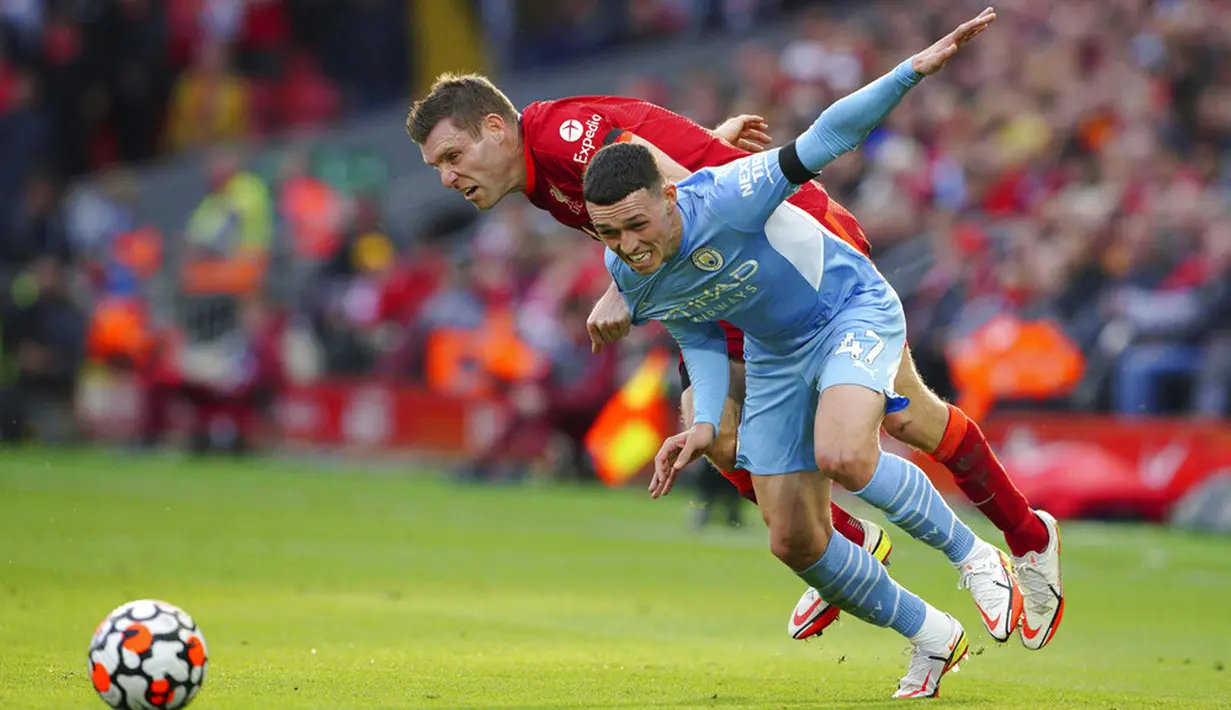Pemain Liverpool James Milner (kiri) berebut bola dengan pemain Manchester City Phil Foden pada pertandingan Liga Inggris di Anfield, Liverpool, Inggris, Minggu (3/10/2021). Pertandingan berakhir imbang 2-2. (Peter Byrne/PA via AP)