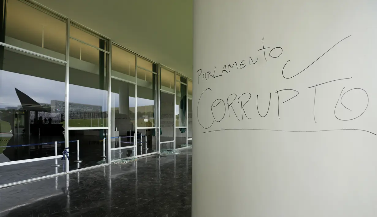 Kata-kata Portugis "Parlemen Korup" menutupi permukaan di luar Senat sehari setelah Gedung Kongres diserbu oleh pendukung mantan Presiden Brasil Jair Bolsonaro di Brasilia, Senin (9/1/2023). Hingga kini, setidaknya sekitar 1.500 orang telah ditahan. (AP Photo/Eraldo Peres)