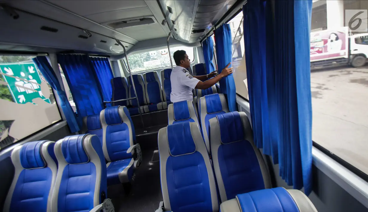Petugas merapikan tirai dalam bus Transjabodetabek Premium milik Perum PPD saat menunggu calon penumpang di Tamini Square, Jakarta, Kamis (14/12). (Liputan6.com/Faizal Fanani)