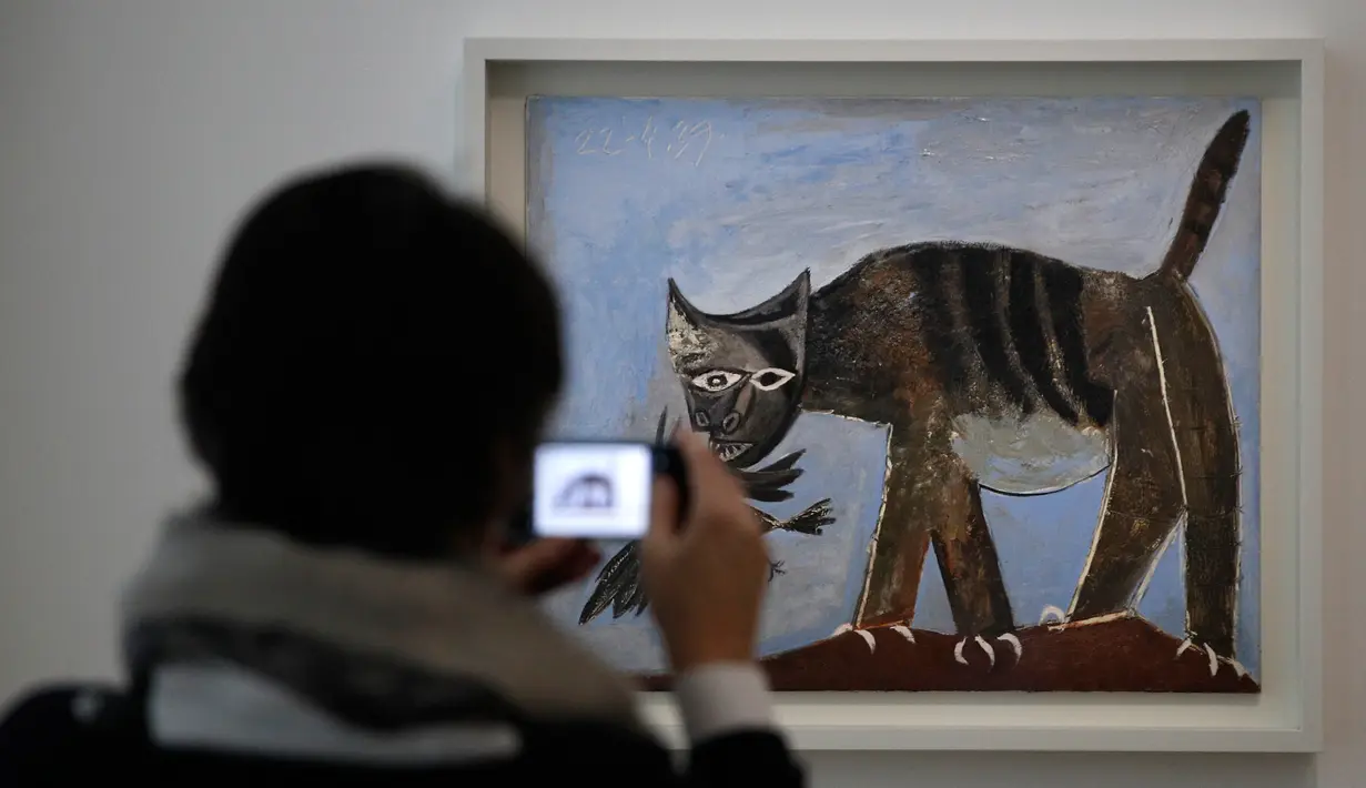 Pengunjung mengambil gambar lukisan berjudul Chat saisissant un oiseau karya Pablo Picasso dalam pameran 'Guernica' di Museum Picasso, Paris, Prancis, Jumat (23/3). Pameran didedikasikan untuk lukisan luar biasa Pablo Picasso. (AP Photo/Christophe Ena)