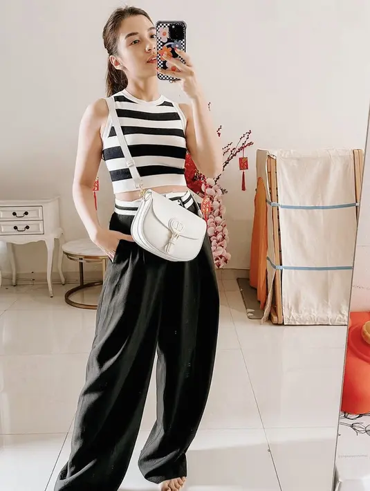 Chelsea juga mengenakan crop top warna hitam putih dipadukan celana hitamnya. Dan membawa sling bag putihnya. credit: Instagram/(@chelseaoliviaa)