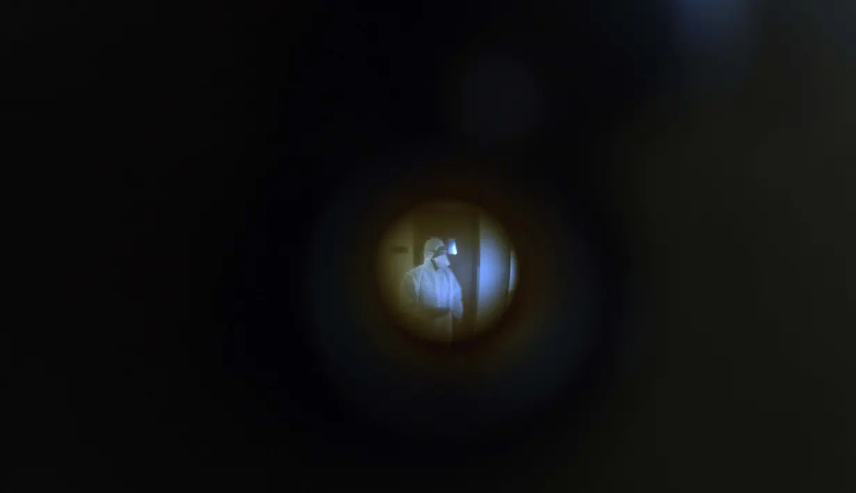 Seorang pekerja sipil terlihat melalui lubang intip fotografer Associated Press Rafiq Maqbool saat menunggu untuk mengisi formulir tes swab di hotel tempat dia dikarantina, Mumbai, India, 24 April 2020. Pada hari ketujuh, tes swab kedua Maqbool menunjukkan hasil negatif. (AP Photo/Rafiq Maqbool)