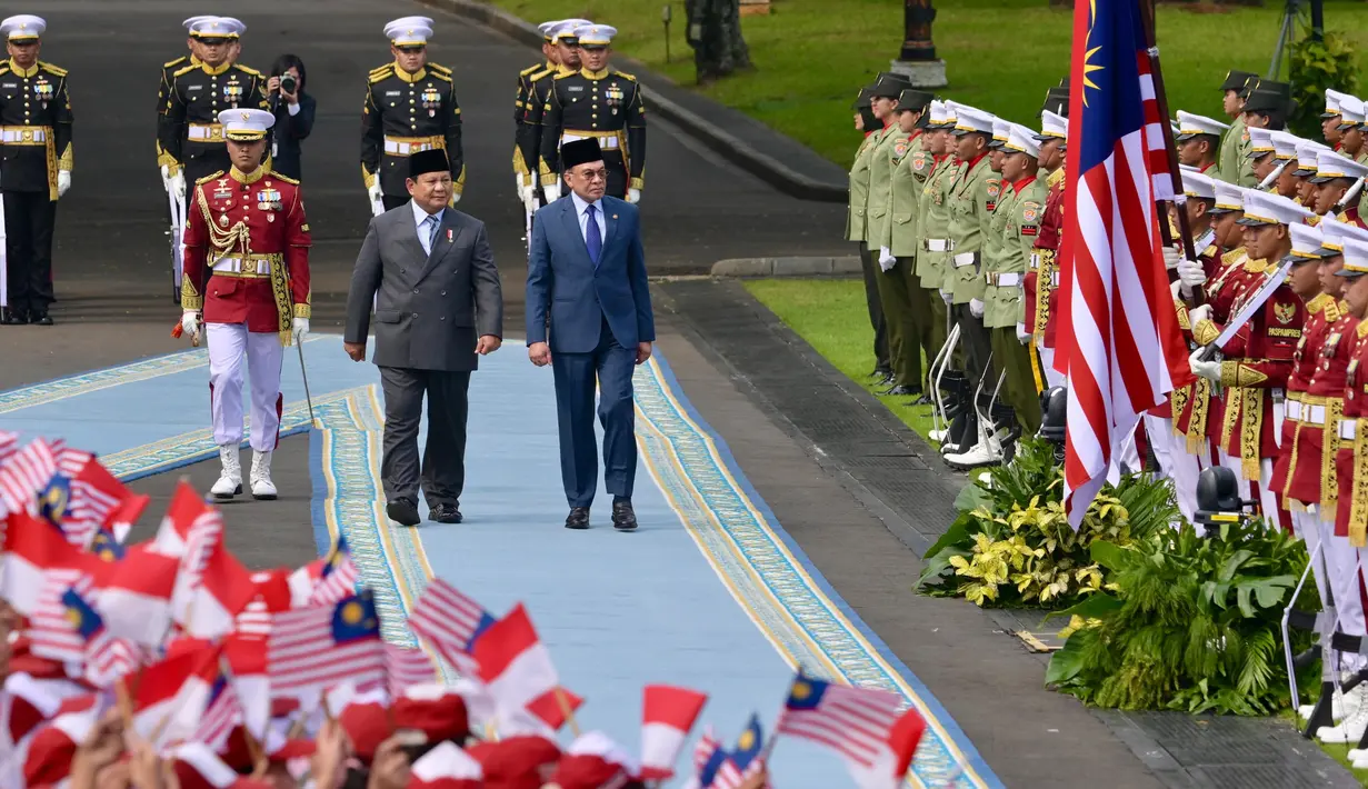 Presiden Republik Indonesia Prabowo Subianto (tengah depan) dan Perdana Menteri (PM) Malaysia Anwar Ibrahim (kanan depan) memeriksa pasukan pengawal presiden sebelum pertemuan mereka di Istana Merdeka di Jakarta pada 27 Juni 2025. (BAY ISMOYO/AFP)