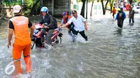 Petugas PPSU membantu pengedara motor untuk melintasi banjir yang terjadi di Jalan Pejaten Raya, Jakarta Selatan, Kamis (21/4/2016). Akibat banjir, kemacetan terjadi cukup panjang di Jalan Pejaten Raya. (Liputan6.com/Yoppy Renato)