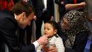 Presiden Prancis Emmanuel Macron menghibur seorang anak saat mengunjungi Graffiti's- Association Le Moulin Vert di Normandia, Prancis (5/4). Pada kunjungannya Presiden Emmanuel Macron berinteraksi dengan anak-anak autis. (AP / Christophe Ena, Pool)