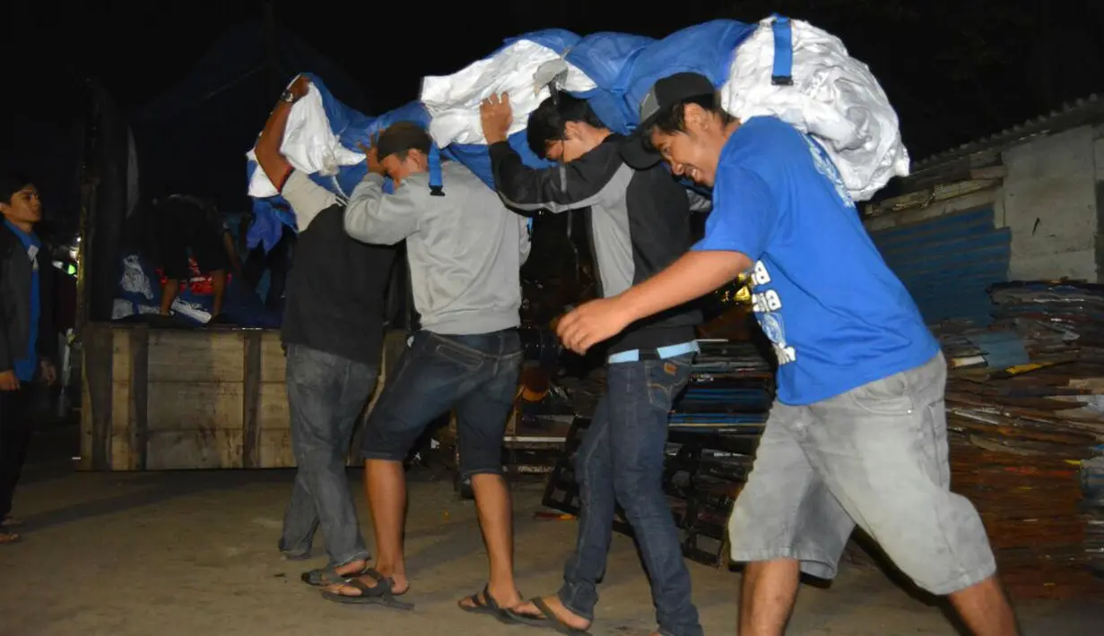 Bendera merah putih raksasa diangkat anggota Aremania menuju truk pengangkut yang akan membawa ke Malang dan Bali. (Bola.com/Aremania)