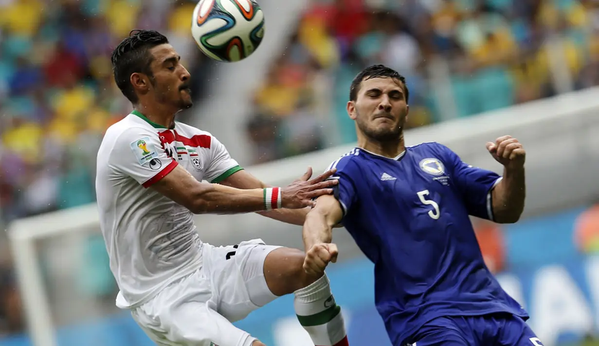 Pemain depan Iran, Reza Ghoochannejhad (kiri) melompat merebut bola dari Sead Kolasinac (Bosnia)  saat berlaga di penyisihan terakhir Piala Dunia 2014 Grup F di Stadion Fonte Nova, Salvador, Brasil, (25/6/2014). (REUTERS/Sergio Perez)