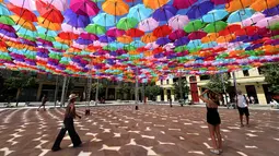 Pengunjung melewati instalasi Umbrella Sky Project di Aix-en-Provence, Prancis, Jumat (28/6/2019). Spot berteduh yang instagramable tersebut merupakan karya seniman Portugis Patricia Cunha. (BORIS HORVAT/AFP)