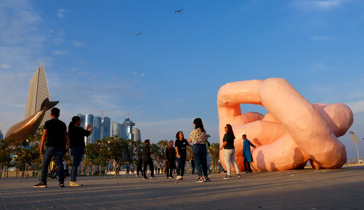 Orang-orang berjalan melewati patung "Gekrose" tahun 2011 karya mendiang seniman Austria Franz West, di corniche tepi laut Doha pada hari kedua Idul Fitri, yang menandai akhir bulan suci puasa Ramadhan. (AFP/Karim Jaafar)