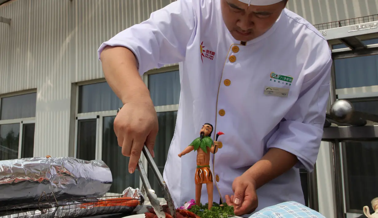 Seorang koki menyajikan makanan dengan patung mini mitos Pemanah Cina Houyi di Dezhou, Shandong Timur, Cina, 2 Agustus 2018. Koki memasak menggunakan kompor tenaga surya. (AP Foto/Fu Ting)