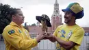 Dua suporter Brasil foto bersama miniatur trofi Piala Dunia saat berada di Kremlin, Moskow, Senin (11/6/2018). Jelang Piala Dunia, para suporter mulai berdatangan ke Rusia. (AP/Dmitri Lovetsky)