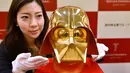 Seorang pegawai toko Tanaka Kikinzoku Jewelry memperlihatkan topeng berlapis emas murni Darth Vader, salah satu tokoh jahat di film Star Wars, di toko utama mereka di distrik perbelanjaan Ginza, Tokyo, Jepang, Selasa (25/4). (AFP Photo/Kazuhiro NOGI)