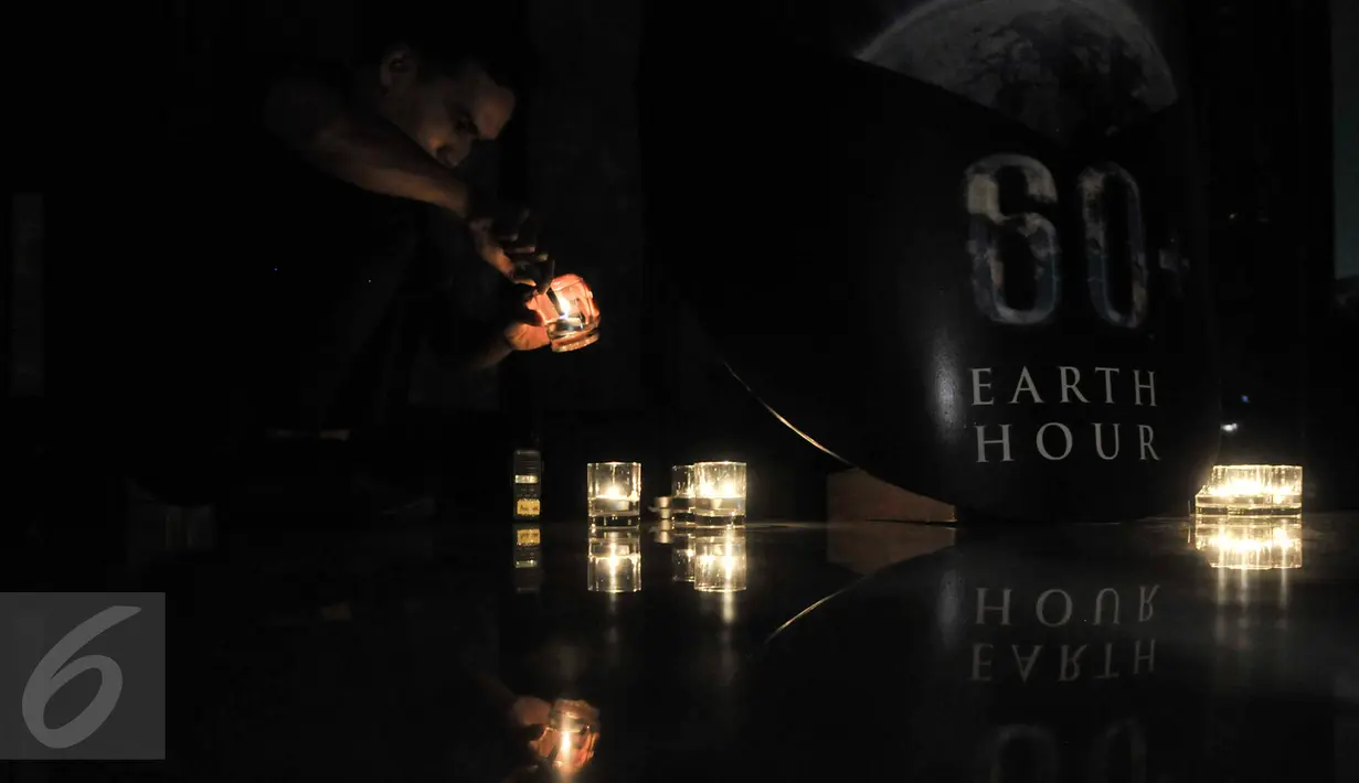 Pekerja menyalakan lilin di lobi Hotel Sheraton Grand Jakarta, Gandaria City, Sabtu (25/3). Sheraton Grand Jakarta Gandaria City Hotel ikut berpartisipasi dalam kampanye penghematan energi Earth Hour 2017 selama satu jam. (Liputan6.com/Yoppy Renato)