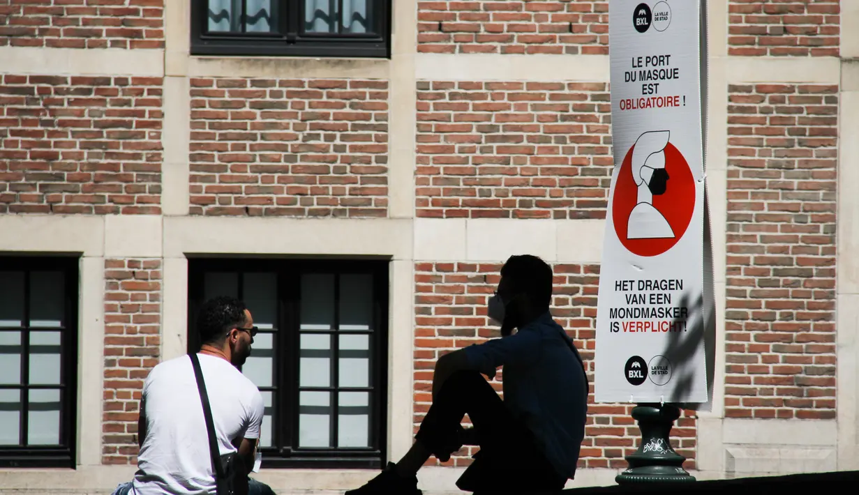 Sejumlah orang beristirahat di dekat spanduk informasi yang mengingatkan masyarakat untuk mengenakan masker di Brussel, Belgia (5/8/2020). Kota Brussel memperluas aturan wajib pakai masker di wilayahnya hingga termasuk di jalan-jalan yang ramai dan zona pejalan kaki. (Xinhua/Zheng Huansong)