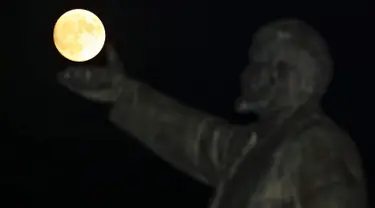 Supermoon terlihat di balik patung pendiri negara Soviet, Vladimir Lenin di Baikonur, Kazakhstan, (13/11). Fenomena ini merupakan bulan paling besar dan terang dalam kurun 70 tahun terakhir. (REUTERS/Shamil Zhumatov)