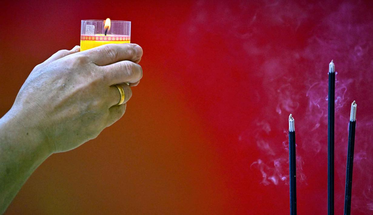 Seorang pria membakar lilin dan dupa saat berdoa di sebuah kuil pada hari pertama Tahun Baru Imlek 2577 Kongzili di Banda Aceh, Provinsi Aceh, pada Selasa 17 Februari 2026. Perayaan Tahun Baru Imlek 2577 Kongzili di Banda Aceh yang jatuh pada hari ini, Selasa, 17 Februari 2026, berlangsung secara khidmat dan sederhana. (CHAIDEER MAHYUDDIN/AFP)