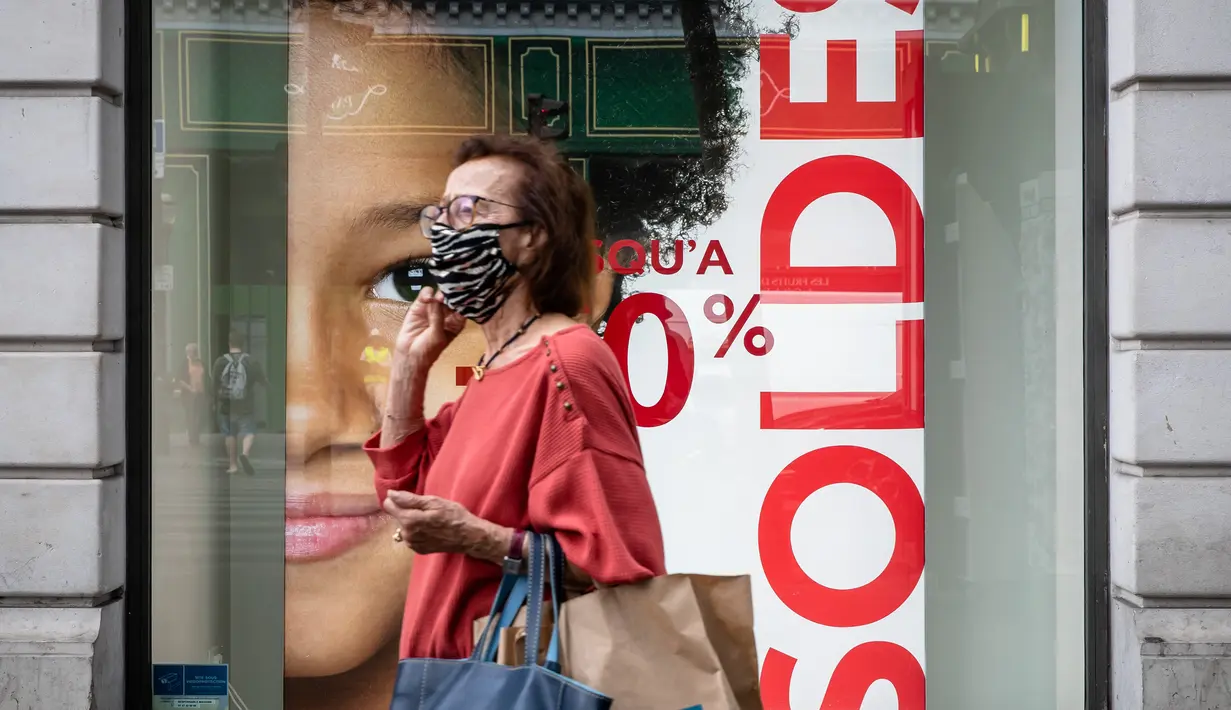 Seorang wanita yang mengenakan masker berjalan melewati tanda diskon pada hari pertama pesta belanja musim panas (summer sale) di Paris, Prancis, pada 15 Juli 2020. Pesta belanja tersebut sedianya akan dimulai pada 24 Juni, namun ditunda akibat wabah COVID-19. (Xinhua/Aurelien Morissard)