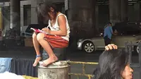 Potret seorang gadis kecil yang tengah mengerjakan pekerjaan rumah (PR) di sebuah jalanan di Filipina menyentuh hati orang-orang.