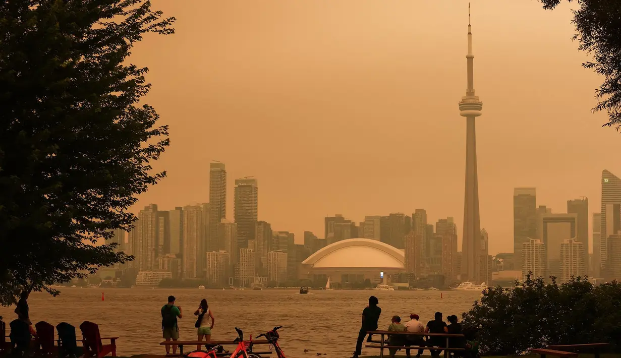 Warga memandang cakrawala pusat kota Toronto dari Kepulauan Toronto saat kabut asap akibat kebakaran hutan di Ontario Utara menyelimuti kota dan menurunkan kualitas udara, Toronto, Ontario, Kanada, Kamis, 15 Juli 2026. (AFP/ Cole Burston)