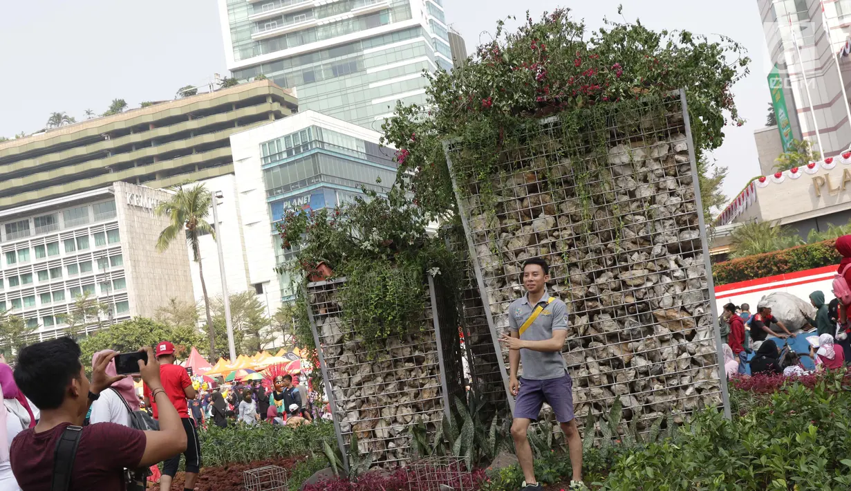 Warga berfoto di area taman dekat Instalasi Gabion saat CFD di kawasan Bundaran Hotel Indonesia, Jakarta, Minggu (25/8/2019). Instalasi Gabion berdiri di lokasi bekas seni anyaman bambu Getah Getih dan diletakkan bebatuan sebagai penghias. (Liputan6.com/Helmi Fithriansyah)