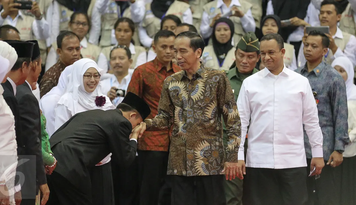 Seorang guru mencium tangan Presiden Joko Widodo (Jokowi) saat hadir dalam Peringatan Hari Guru Nasional 2015, Istora Senayan, Jakarta, Selasa (24/11). Peringatan hari guru tahun ini mengangkat tema 'Guru Mulia Karena Karya'. (Liputan6.com/Faizal Fanani)