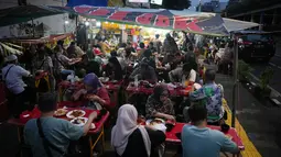 Aneka menu lauk untuk Nasi Kapau dihidangkan seperti gulai tambusu, ayam pop, rendang, jengkol balado, dendeng batokok dan masih banyak lagi. Tampak dalam foto, orang-orang berbuka puasa di sebuah warung makan pinggir jalan pada hari kedua bulan suci Ramadan 1447 Hijriah di Jakarta, Jumat 20 Februari 2026. (AP Photo/Dita Alangkara)