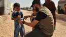 <p>Seorang sukarelawan membagikan pakaian kepada anak-anak Suriah di sebuah kamp di pinggiran kota Dana yang dikuasai pemberontak, di sebelah timur perbatasan Turki-Suriah di provinsi barat laut Idlib (30/4/2022). Umat Islam seluruh dunia bersiap untuk merayakan Idul Fitri yang menandai akhir bulan puasa Ramadhan. (AFP/Aaref Watad)</p>