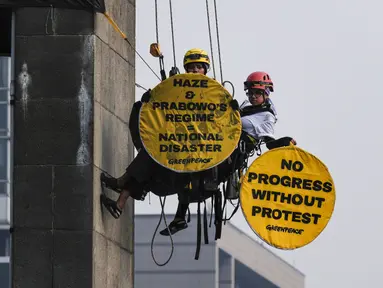 Aktivis Greenpeace Indonesia bergelantungan di Patung Selamat Datang sambil membentangkan poster berisi pesan protes di kawasan Bundaran Hotel Indonesia, Jakarta, Selasa (20/10/2026). Aksi tersebut digelar bertepatan dengan dua tahun pelantikan Presiden Prabowo Subianto. Para aktivis mendesak pemerintah mengambil langkah untuk mengatasi krisis iklim yang kian memburuk dan kenaikan biaya hidup. (BAY ISMOYO/AFP)