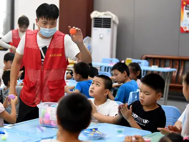 Sukarelawan bermain bersama anak-anak di tempat pengungsian sementara Sekolah Menengah No.168, Hefei, Provinsi Anhui, China, Rabu (29/7/2020). Lebih dari 300 penduduk desa di Kota Sanhe, Hefei, dievakuasi ke sekolah itu akibat terdampak banjir. (Xinhua/Liu Junxi)