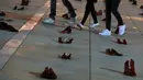 Orang-orang berjalan melewati instalasi ratusan sepatu merah untuk memprotes kekerasan terhadap perempuan di kota pesisir Tel Aviv, Selasa (4/12). Sepanjang tahun ini, 24 perempuan Israel tewas akibat tindakan kekerasan dalam rumah tangga. (JACK GUEZ/AFP)