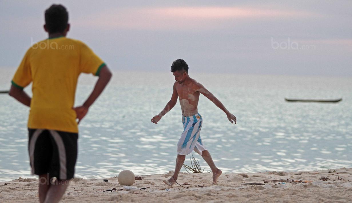 Seorang pemuda mencoba melakukan tembakan saat bermain bola dekat pantai di Desa Matwaer, Kei Kecil, Maluku (25/12/2017). Bermain bola di pasir menjadi daya tarik tersendiri bagi anak-anak. (Bola.com/Nick Hanoatubun)