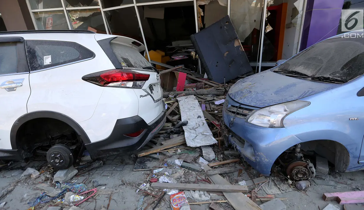 Sebuah mobil Toyota Rush dan Avanza menjadi incaran jarahan korban gempa dan tsunami di Palu Grand Mal, Palu, Jumat (5/10). Warga korban gempa bumi mengambil ban dan interior mobil. (Liputan6.com/Fery Pradolo)