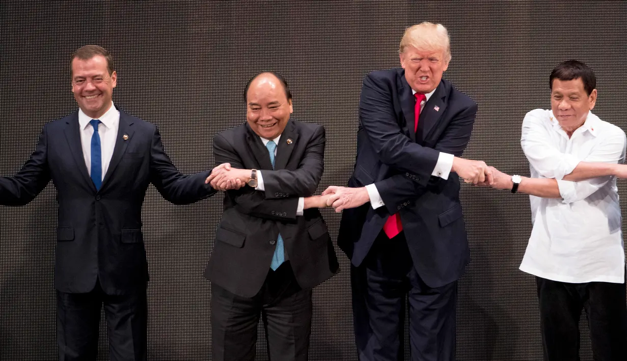 Ekspresi Presiden AS, Donald Trump saat bersalaman khas ASEAN dengan para pemimpin lainnya di penghujung upacara pembukaan KTT ASEAN di Manila, Filipina, Senin (13/11). Trump kesulitan menempatkan tangannya di posisi yang pas. (AP/Andrew Harnik)