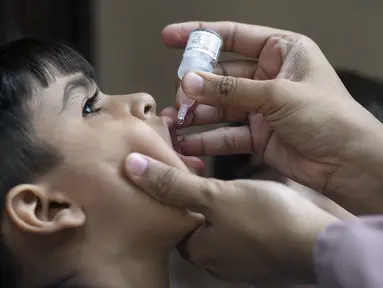 Petugas kesehatan memberikan vaksin polio kepada seorang anak selama kampanye vaksinasi polio dari pintu ke pintu di daerah kumuh di Karachi, Paksistan, Senin (23/5/2022). Pakistan meluncurkan upaya anti-polio baru pada hari Senin, lebih dari seminggu setelah pejabat mendeteksi kasus ketiga tahun ini di wilayah barat laut negara itu yang berbatasan dengan Afghanistan. (Asif HASSAN / AFP)