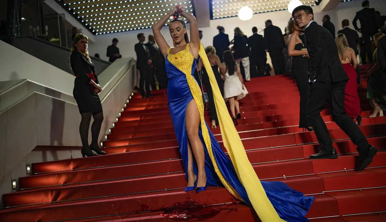 Seseorang dengan warna Ukraina menuangkan zat merah ke tubuhnya pada pemutaran perdana film 'Aside' selama Festival Film Cannes ke-76, di Cannes, Prancis selatan, Minggu, 21 Mei 2023. (AP Photo/Daniel Cole)