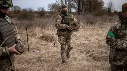 Anggota regu penjinak bom berjalan di ladang ranjau dekat Brovary, timur laut Kiev, di tengah invasi militer Rusia pada 14 April 202. Rusia sudah menarik tentara mereka dari Kiev dan mengalihkan sebagian besar fokus perangnya ke wilayah Ukraina timur pada akhir Maret. (FADEL SENNA/AFP)