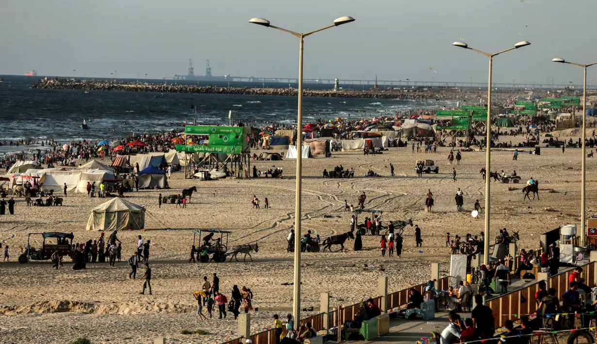 <p>Sejumlah warga Palestina menikmati suasana pantai Kota Gaza, Jumat (22/6). Pantai Gaza menjadi pelipur bagi penduduk yang tak punya pilihan berwisata ke luar kota atau luar negeri. (AFP PHOTO/MAHMUD HAMS)</p>