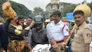 Seorang seniman berpakaian seperti "Yamaraj" (R), dewa kematian Hindu, memakaikan helm kepada pengendara motor saat  kampanye 'Road Safety Week' di Bangalore (10/7). (AFP Photo/Manjunath Kiran)