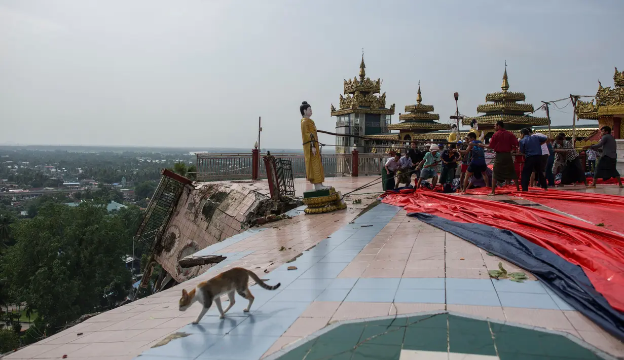 Warga menarik patung Buddha akibat hujan dan tanah longsor yang merusak pagodha di puncak bukit Kyeik Than Lan, Myanmar (18/6). Beberapa wilayah di negara bagian Mon, menghadapi banjir akibat hujan deras sejak akhir pekan lalu. (AFP PHOTO / Ye Aung Thu)