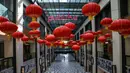 Seorang pembeli berjalan di lorong mal dengan dekorasi lentera untuk perayaan Tahun Baru Imlek di Kuala Lumpur, Malaysia, Rabu (3/2/2021). Imlek tahun ini jatuh pada tanggal 12 Februari 2021. (Mohd RASFAN/AFP)