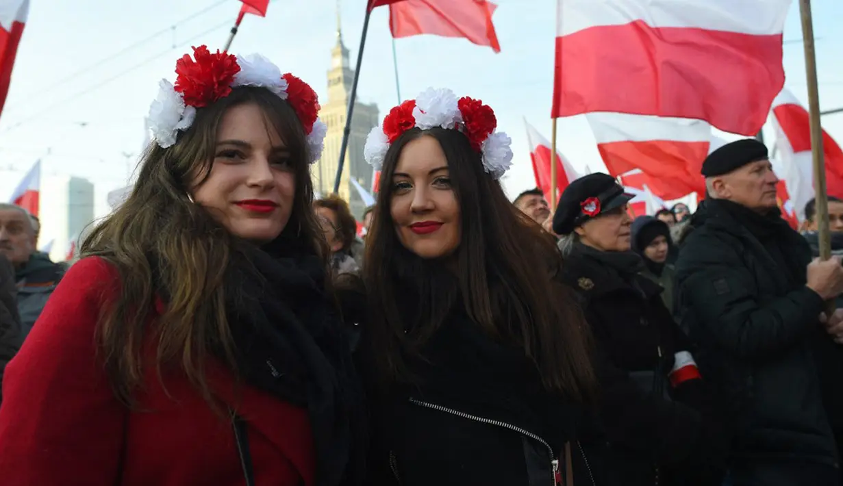 <p>Orang-orang mengibarkan bendera nasional Polandia saat pawai untuk menandai Hari Kemerdekaan Nasional Polandia di Warsawa, Polandia, 11 November 2021. Hari Kemerdekaan Nasional Polandia dirayakan pada 11 November untuk memperingati ulang tahun Republik Polandia Kedua. (Adam Chelstowski/AFP)</p>