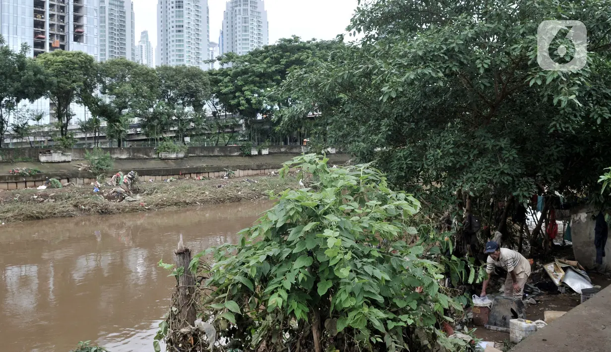 Salah seorang warga bantaran merapikan barang-barang usai banjir merendam gubuk miliknya yang berada di pinggir Kanal Banjir Barat (KBB), Jakarta, Rabu (8/1/2020). (merdeka.com/Iqbal S Nugroho)