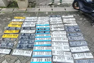 Seorang tukang tambal ban yang membuka lapak di belakang Lotte Mart, Kelapa Gading, Jakarta Utara (Jakut), sibuk mengumpulkan pelat nomor di tengah kondisi banjir. (Foto: Antara)