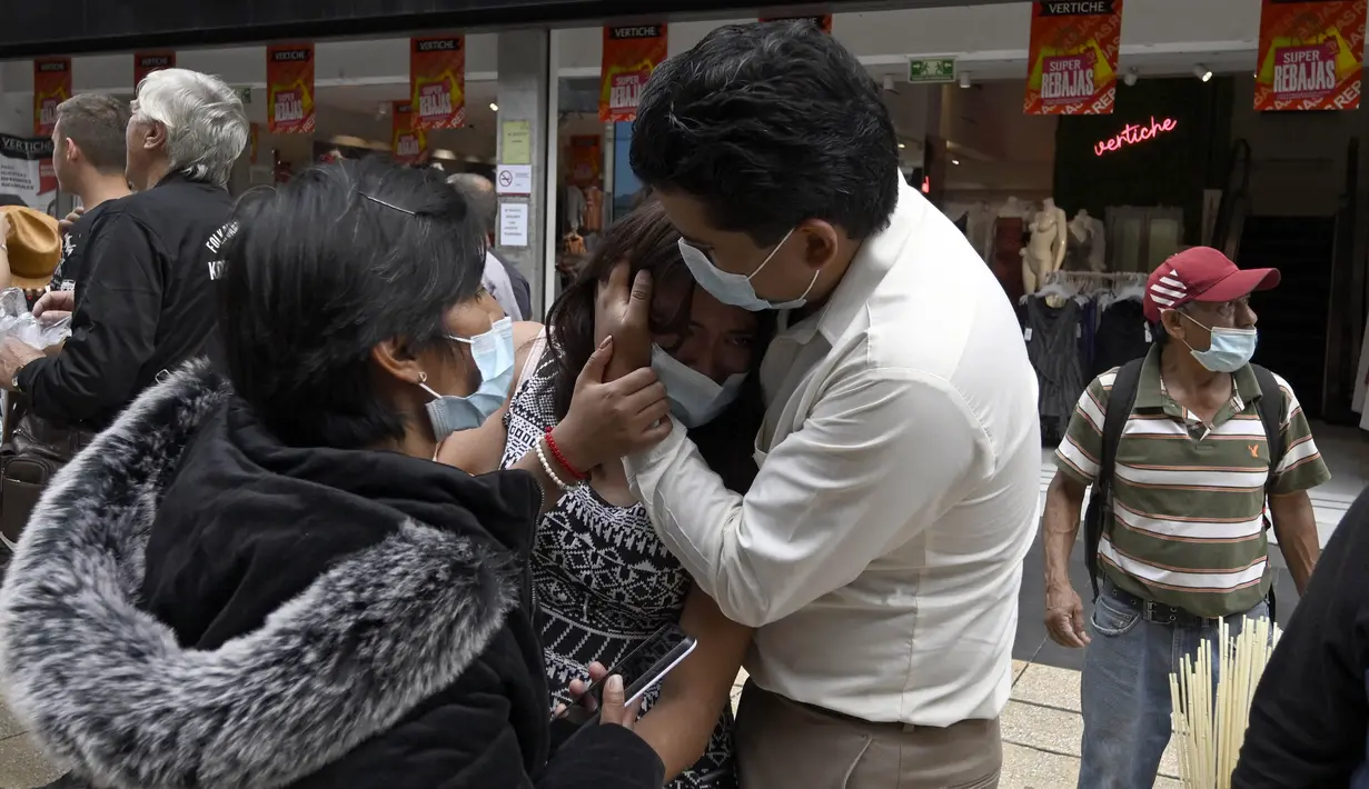 Seorang perempuan ditenangkan oleh seorang pria setelah gempa bumi di Mexico City pada Senin (19/9/2022). Lampu lalu lintas berhenti bekerja, dan orang-orang mencengkeram ponsel mereka, mengirim pesan teks atau menunggu panggilan masuk. (Photo by Alfredo ESTRELLA / AFP)