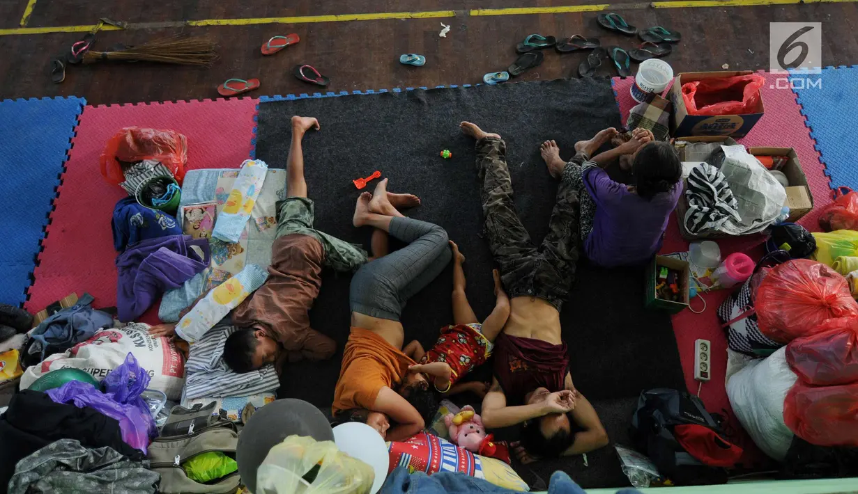 Warga beristirahat di lokasi pengungsian di GOR Suweca, Klungkung, Bali, Selasa (26/9). Hingga kini tercatat, 57.418 jiwa mengungsi di 357 lokasi menyusul peningkatan aktifitas Gunung Agung yang masih berstatus awas. (Liputan6.com/Gempur M Surya)
