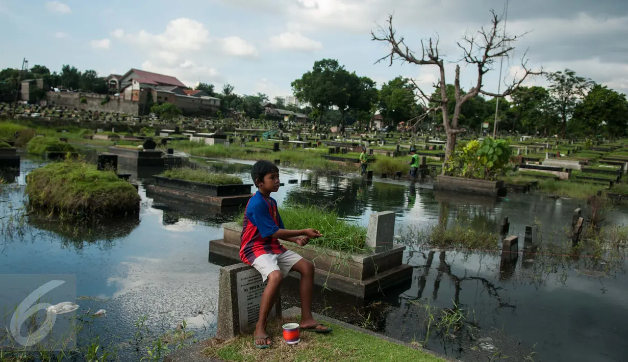 Seorang anak bermain layang-layang diatas makam di Tempat Pemakaman Umum (TPU) Tanah Kusir, Jakarta, Selasa (25/4). (Liputan6.com/Gempur M. Surya)