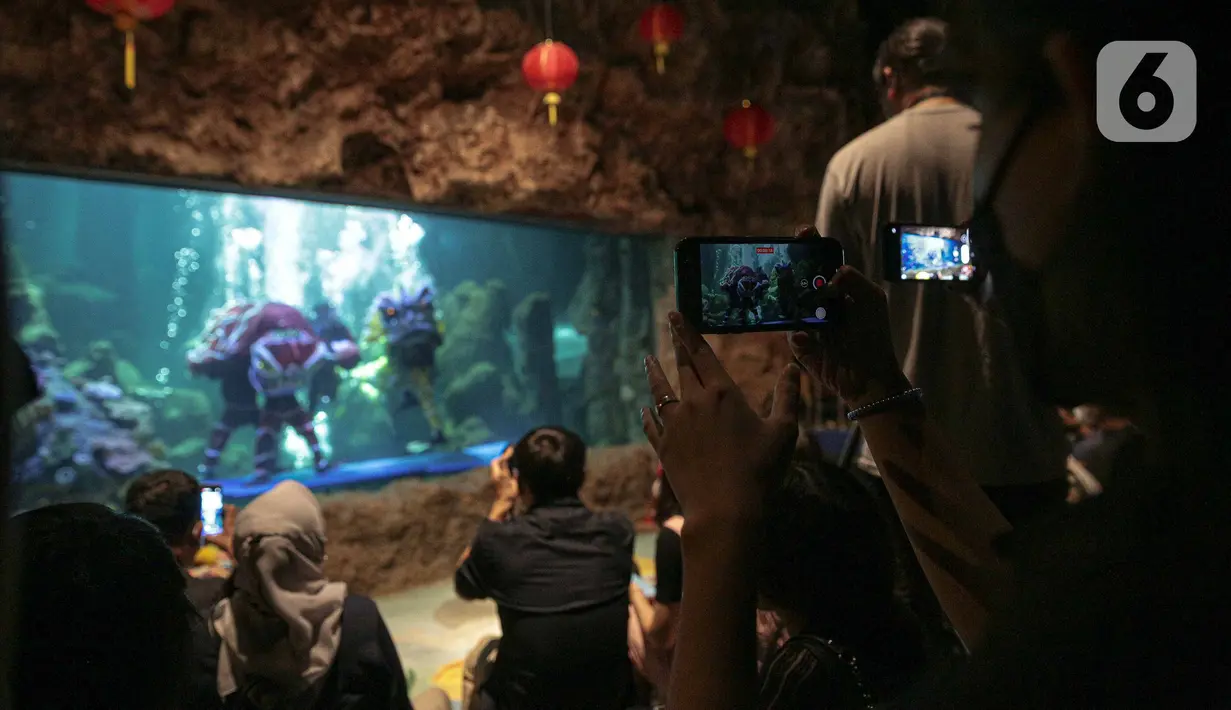 Pengunjung menyaksikan atraksi barongsai dan liong di akuarium SeaWorld Ancol, Jakarta, Senin (24/1/2022). Atraksi barongsai dan liong tersebut digelar dalam rangka memeriahkan perayaan tahun baru Imlek 2573. (Liputan6.com/Faizal Fanani)