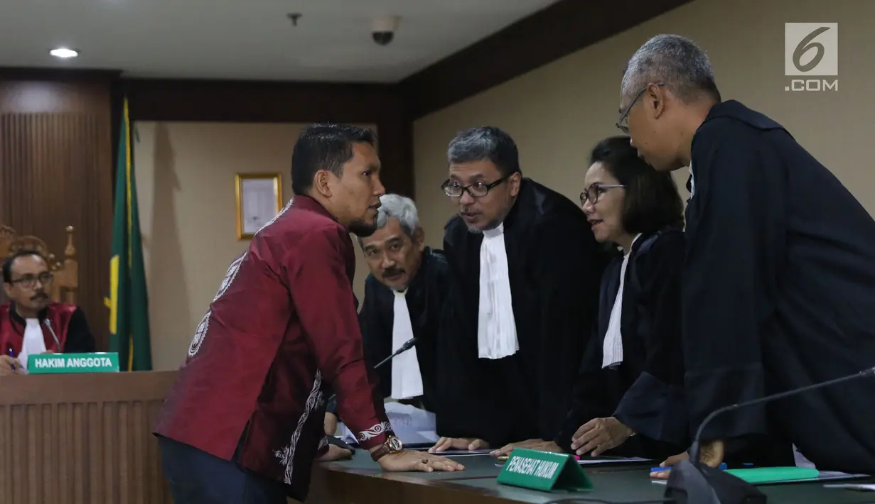 Bupati Bener Meriah, Ahmadi (baju batik) berbincang dengan penasehat hukumnya saat sidang perdana kasus dugaan suap alokasi dan penggunaan anggaran Dana Otonomi Khusus Aceh di Pengadilan Tipikor, Jakarta, Kamis (27/9). (Liputan6.com/Helmi Fithriansyah)