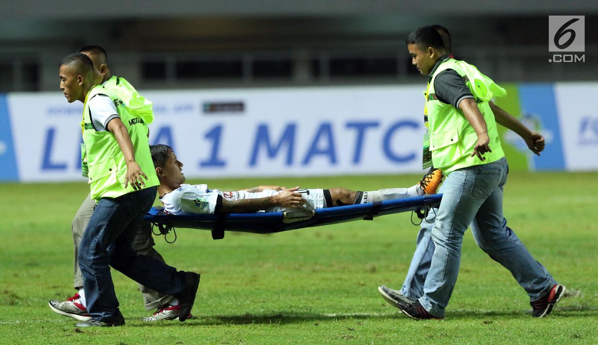 Pemain depan Bali United, Irfan Bachdim ditandu keluar lapangan saat laga melawan PS TNI dilanjutan Liga 1 Indonesia di Stadion Pakansari, Kab Bogor, Senin (10/7). Laga dimenangkan Bali United dengan skor 4-3. (Liputan6.com/Helmi Fithriansyah)